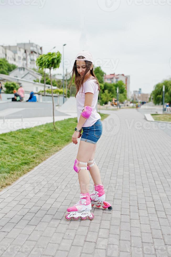 retrato de una joven guapa con ropa informal patinando en la acera del parque. foto