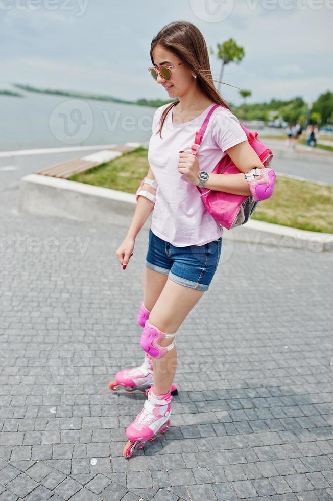 retrato de una joven guapa con ropa informal patinando en la acera del parque. foto