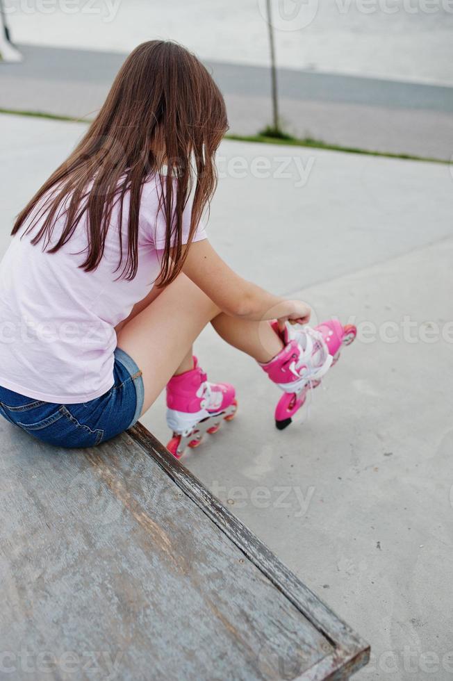 Young woman putting on rollerblades outdoor. photo