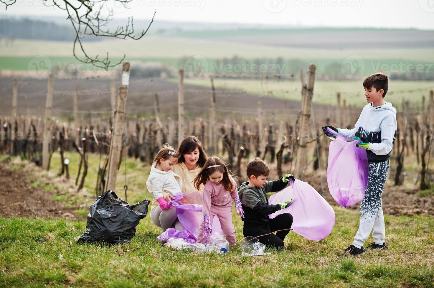 familia con bolsa de basura recogiendo basura mientras limpia en los viñedos. conservación ambiental y ecología, reciclaje. foto