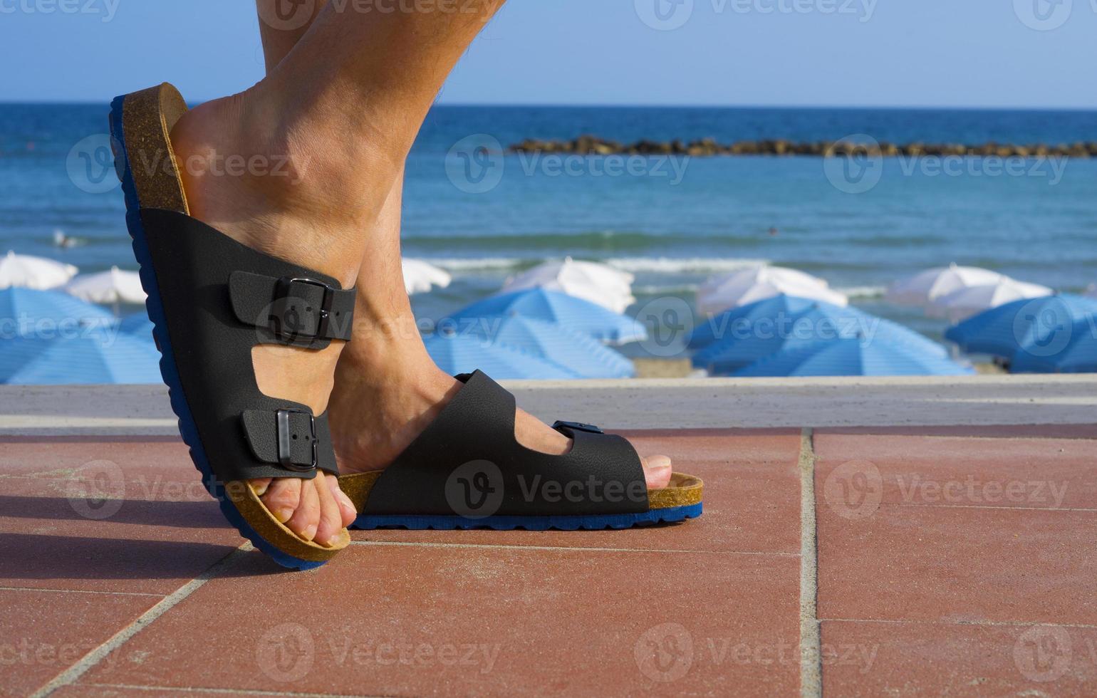Black and blue men's sandals walking on the beach in summer vacation time photo