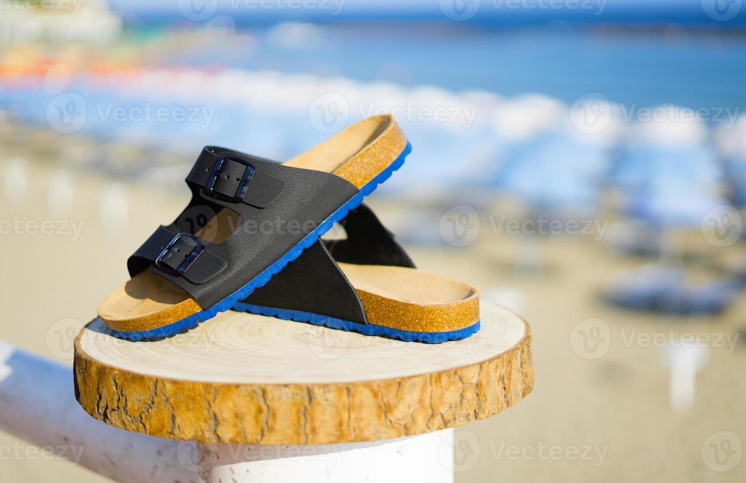 azul con sandalias de hombre negro sobre un tronco de madera en verano foto