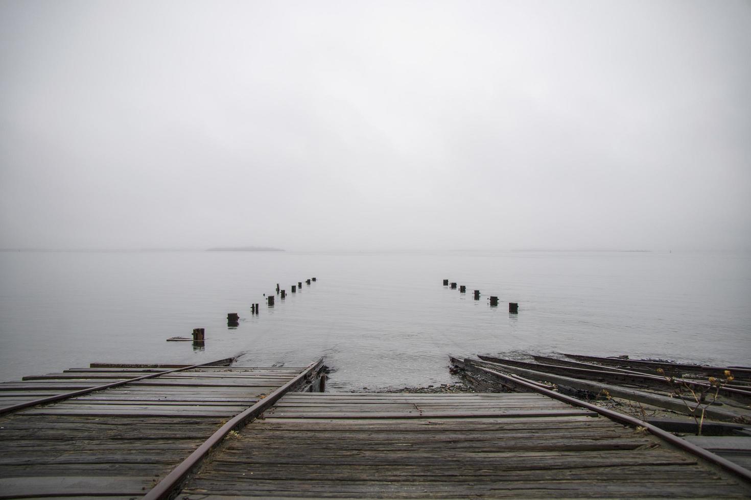 viejo muelle hundido en el océano en un día de niebla foto