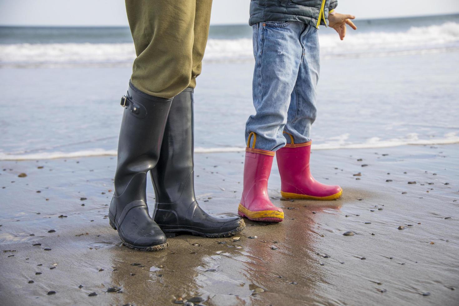 niña con botas rosas caminando en una playa foto