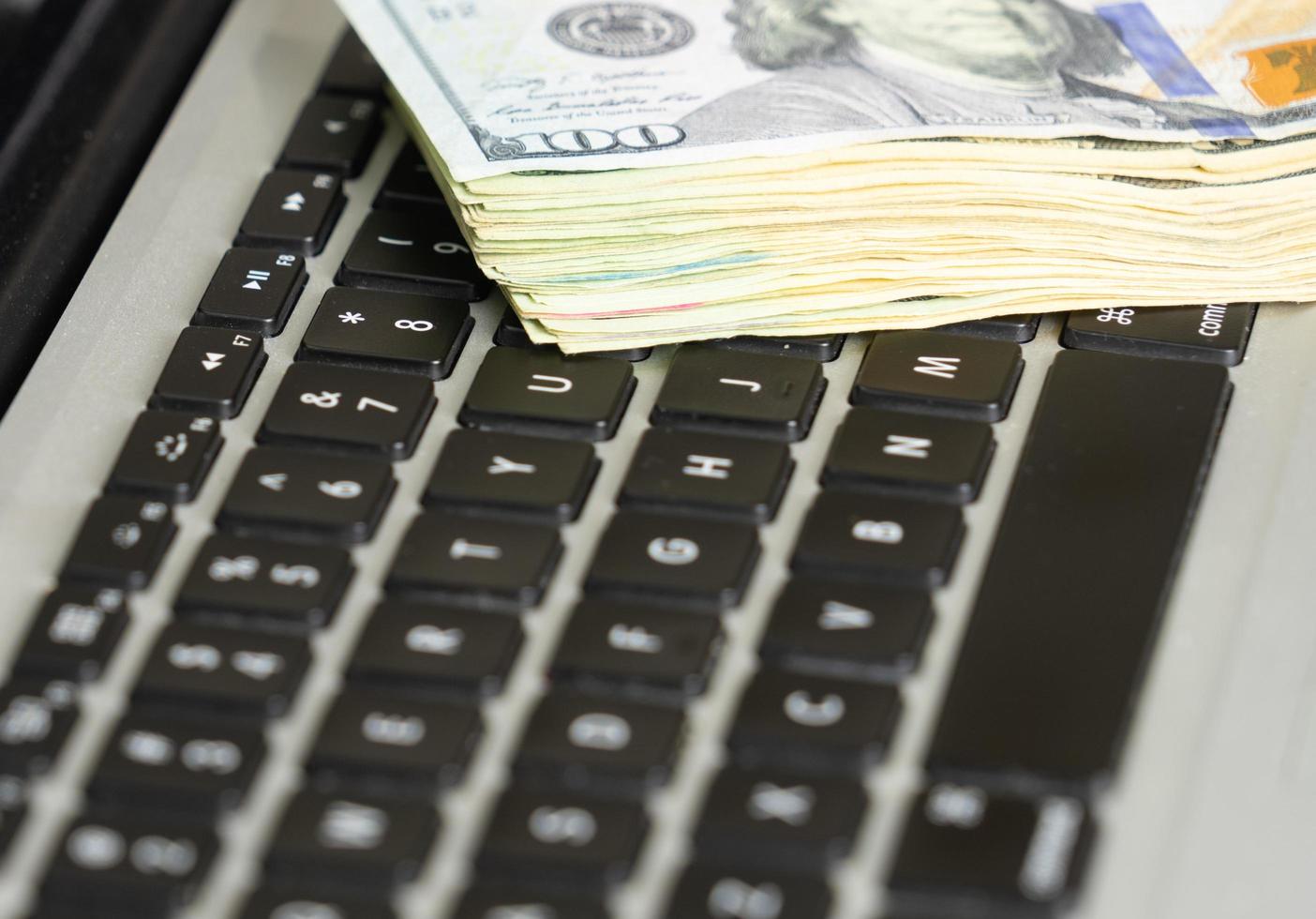 Close up of dollar banknotes on laptop keyboard, business concept photo