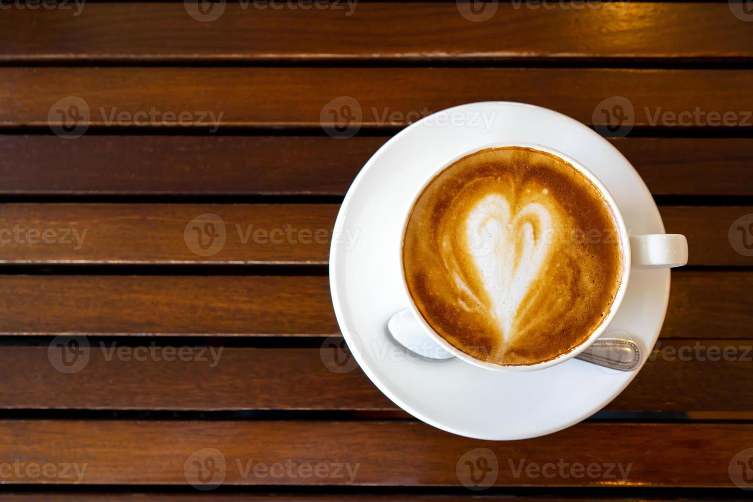 vista superior de café con leche o café capuchino en una taza blanca con un hermoso arte de café con leche de árbol en una mesa de madera. foto