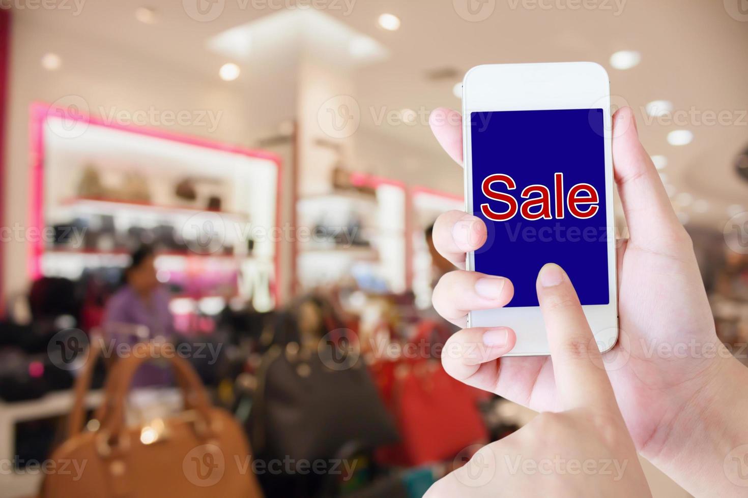 hand hold mobile phone blurred in shopping mall background photo