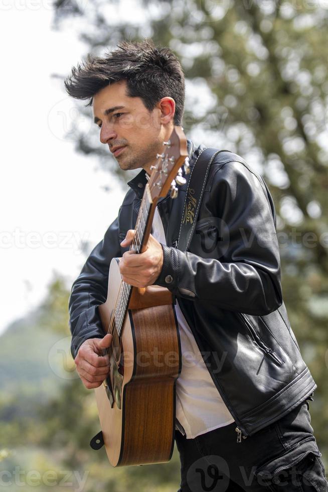 niño tocando la guitarra al aire libre en la naturaleza foto