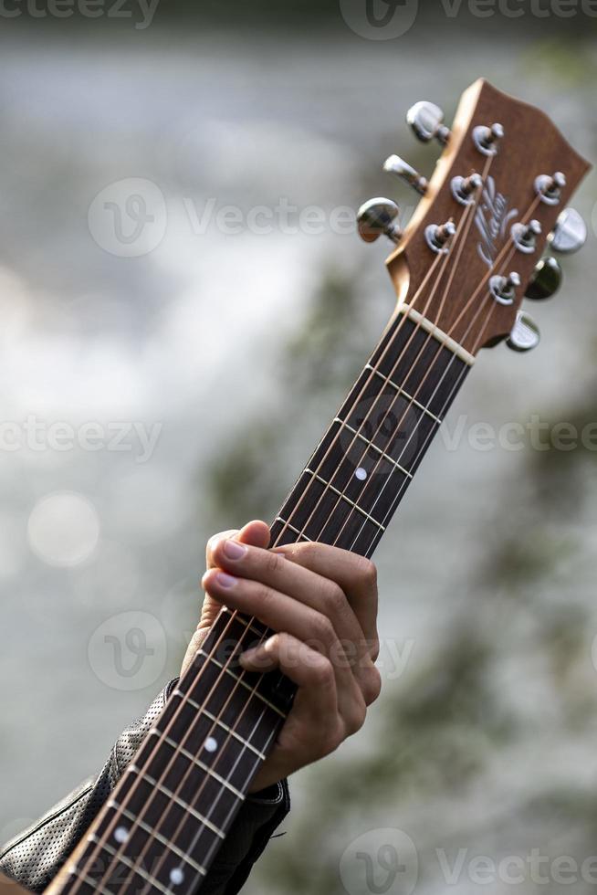 detail hand plays guitar river background photo