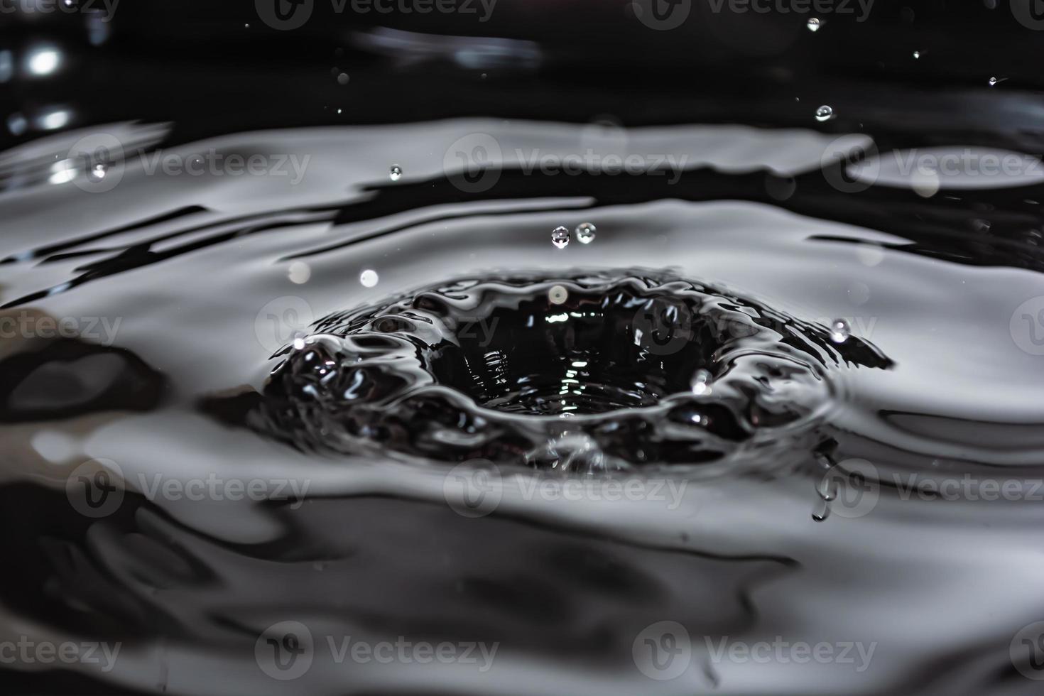 salpicaduras y ondas de gotas de agua que caen sobre la superficie de un líquido. foto