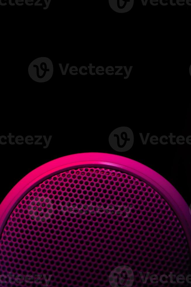 Musical speaker illuminated with lilac crimson on a black background. Vertical background. photo