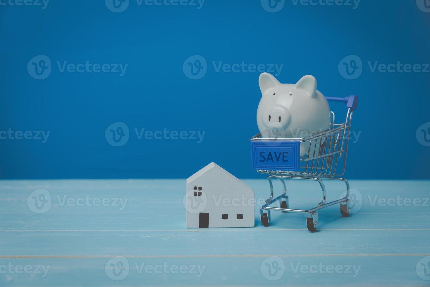 A shopping car with a white pig piggy bank and model white house for saving money investment. house trading concept. Housing, bank loans to buy a house, real estate investment, real estate business. photo