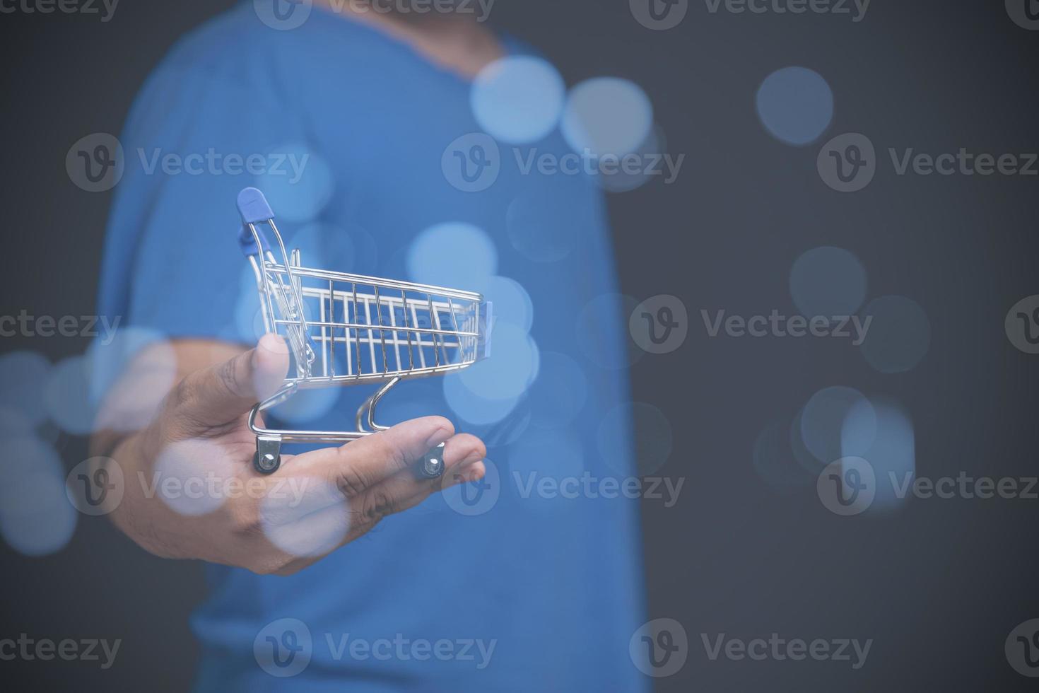 A man holding a toy shopping cart empty on hand with copy space for text or design, background. sale, discount, shopping online concept. Consumer society trend. photo