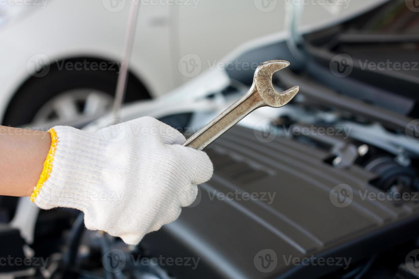 mano con llave reparando motor de coche foto