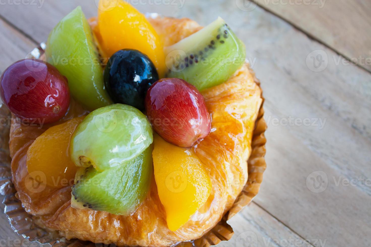 close up danish pastry with fruit on wood table photo