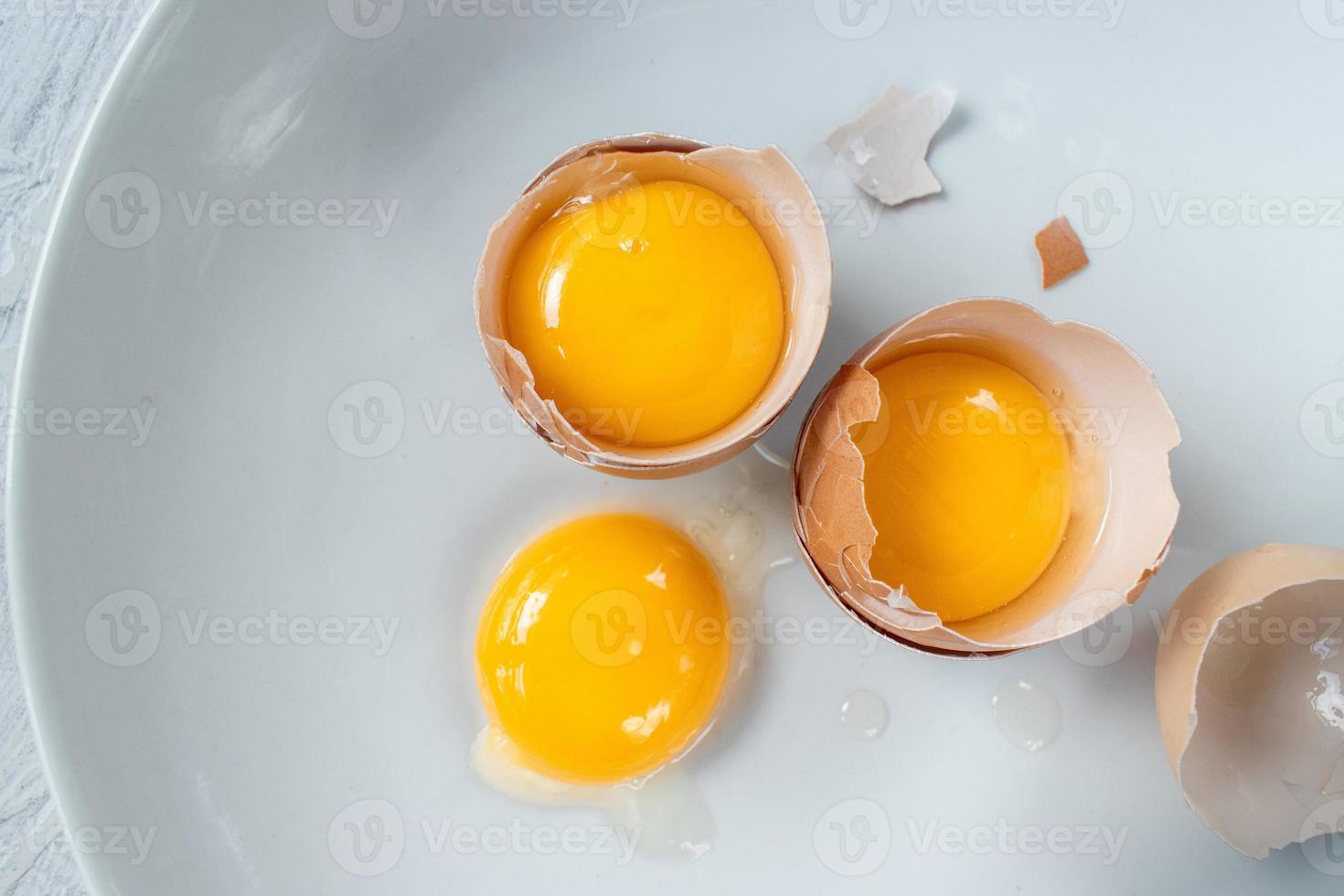 group of egg yolks in broken shells on white background flat lay photo