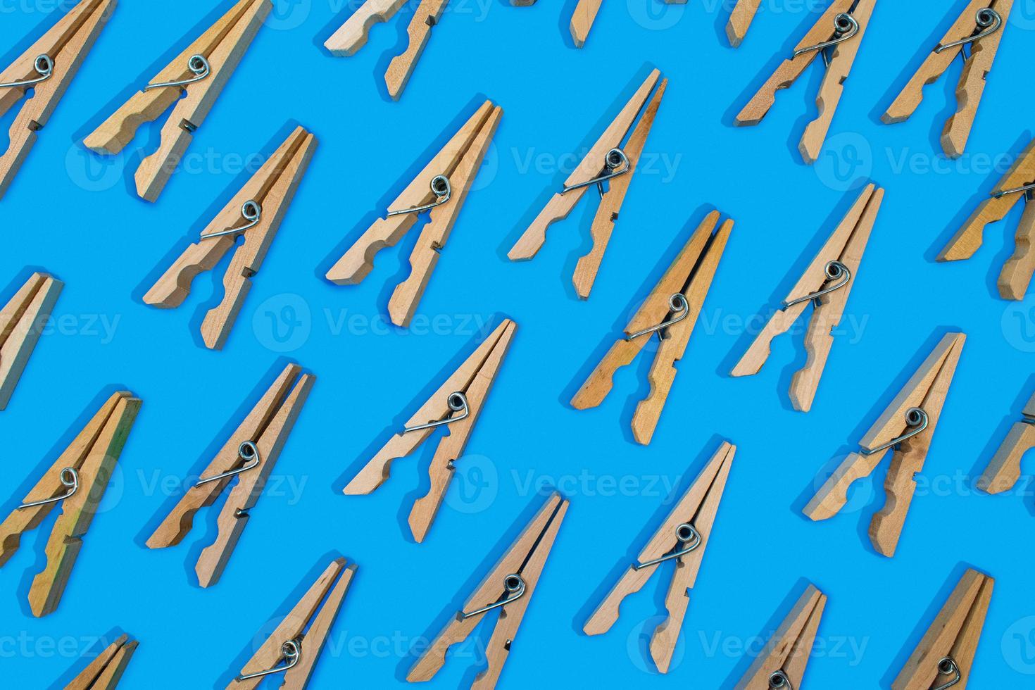 opened clothespins laid out in pattern on vibrant blue background photo