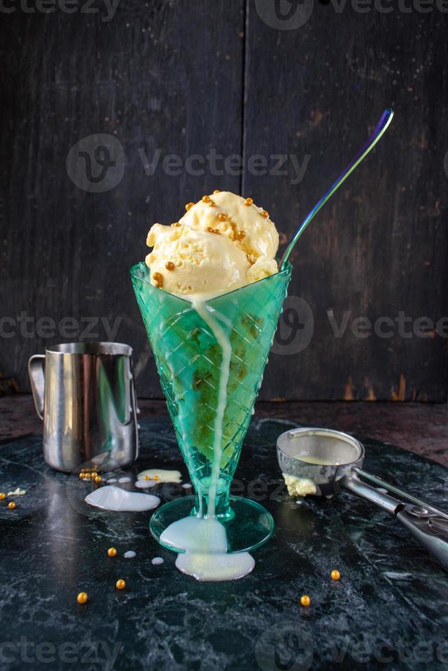 Helado derretido en vaso alto con cuchara y chispas foto