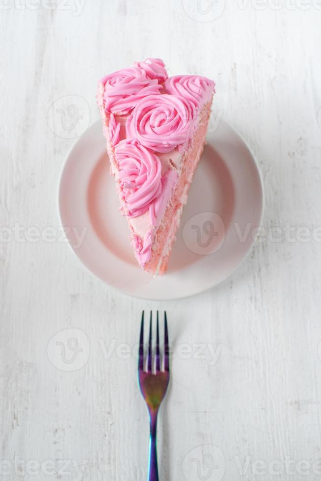 festive thin slice of pink birthday cake with icing flowers and fork flat lay photo