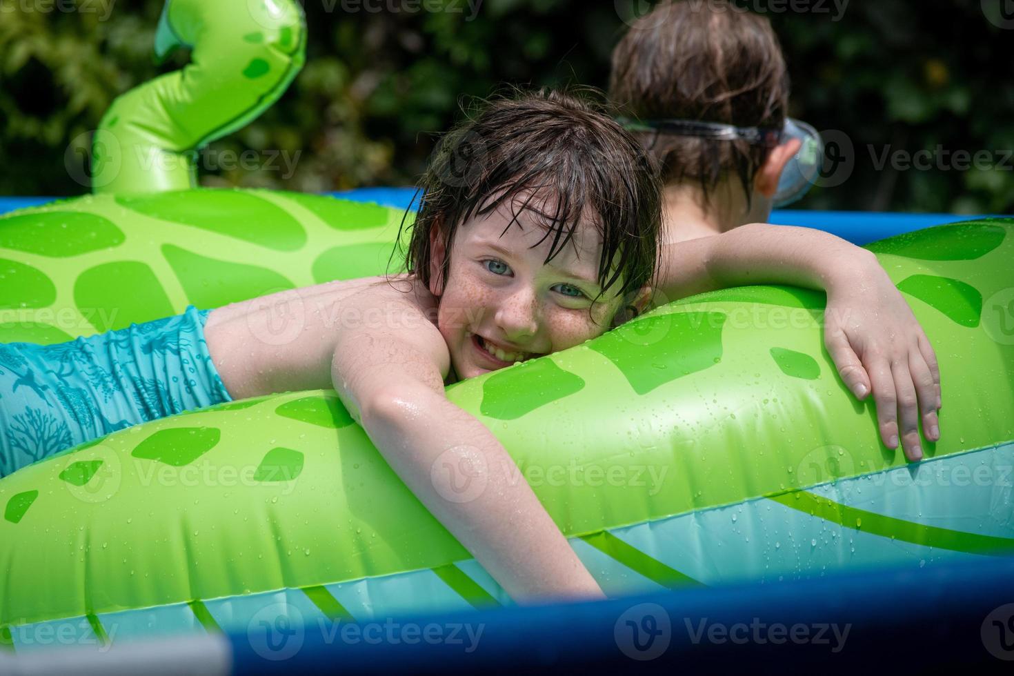 smiling happy young girl lounging on vibrant pool float at sunny backyard pool photo