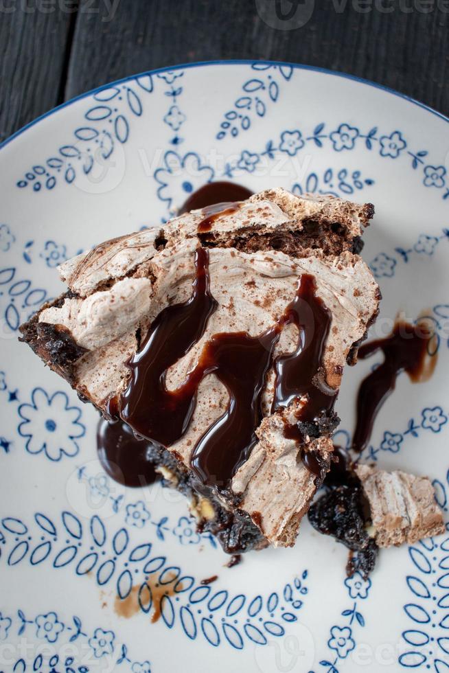 rebanada de postre de brownie al horno cubierto con merengue y remolinos de chocolate y rociado con sirope de chocolate foto