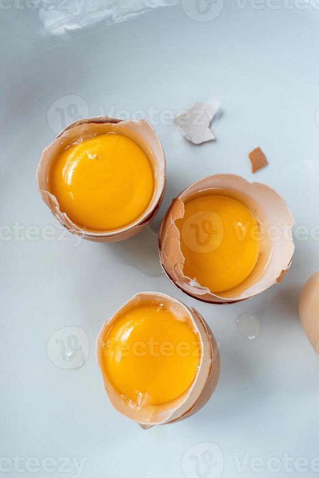 group of egg yolks in broken shells on white background flat lay photo