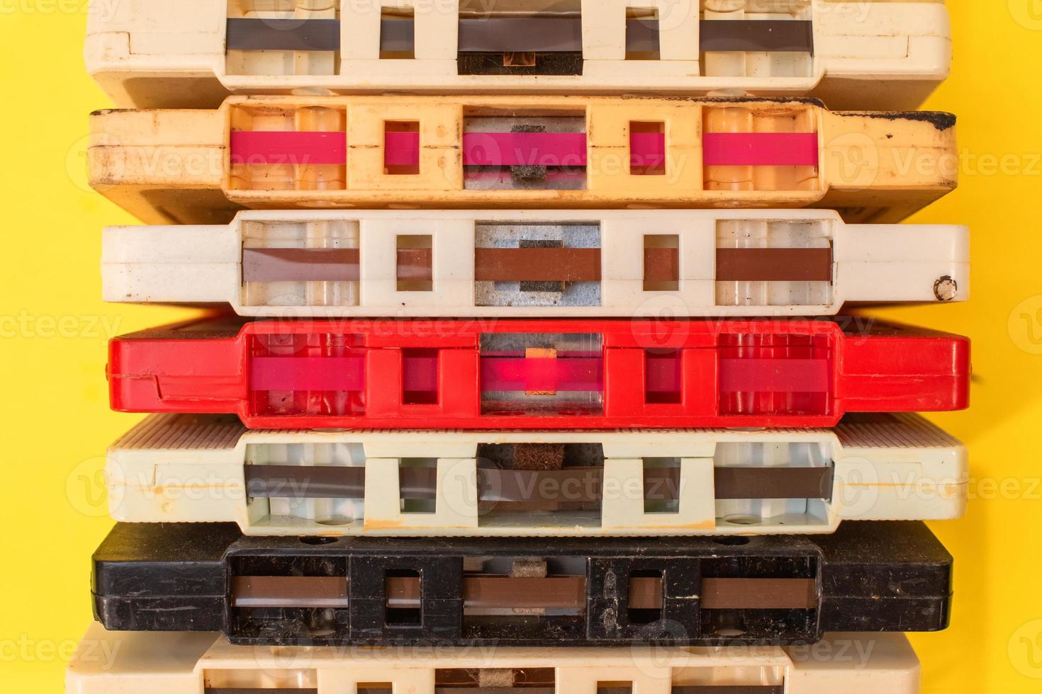 stack of old retro cassette tapes with tape ends showing on yellow background photo