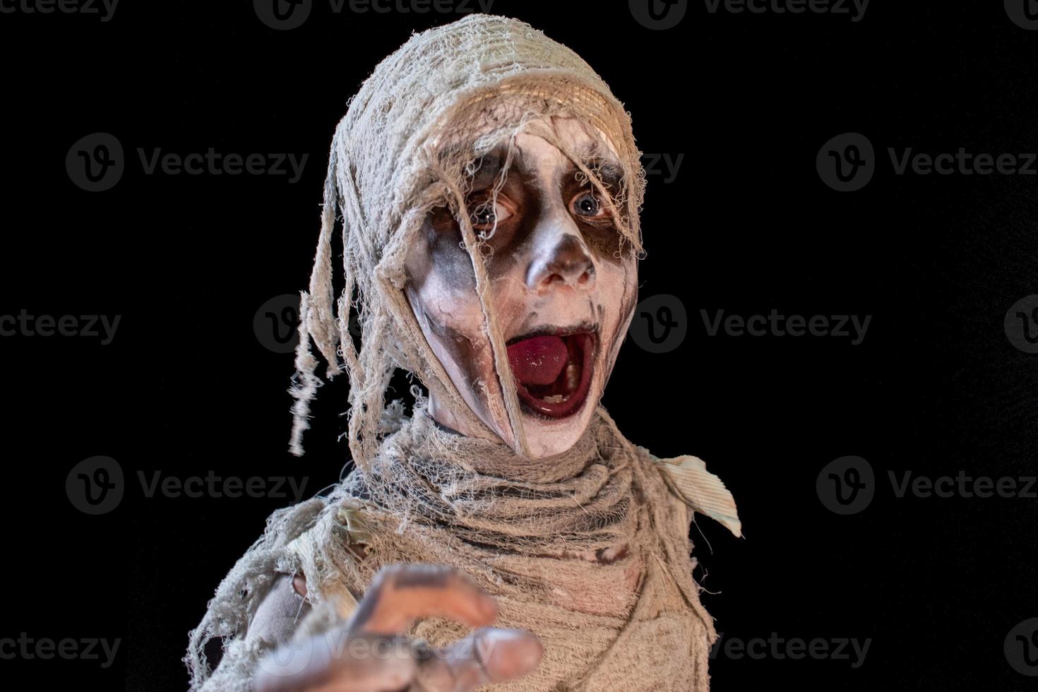 retrato de estudio de un joven disfrazado de halloween, cosplay de una pose de momia aterradora sobre un fondo negro aislado foto