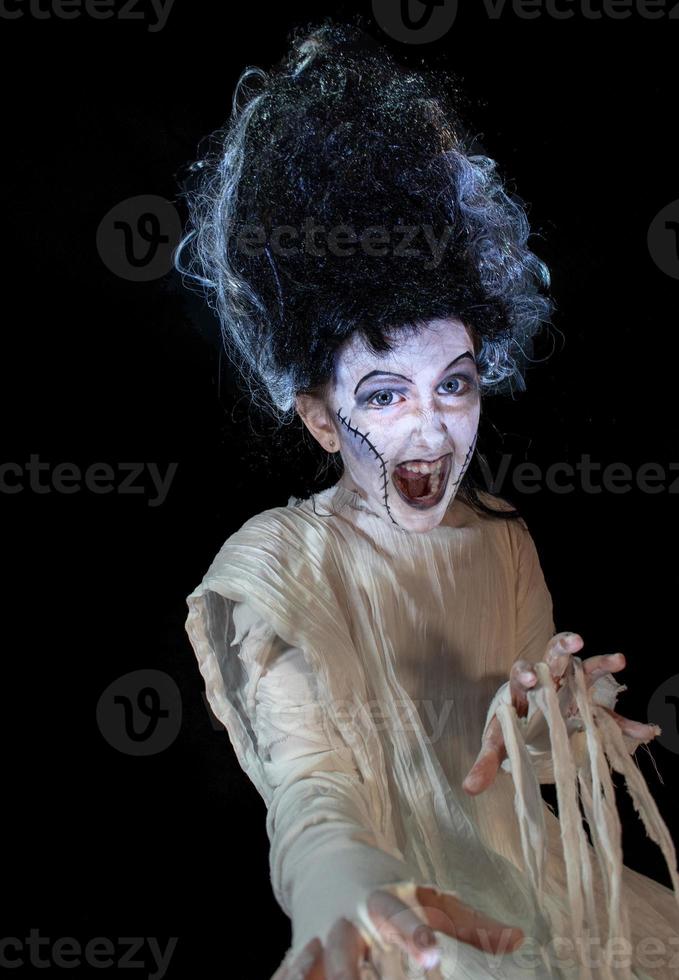 studio shot portrait of young girl in costume dressed as a Halloween, cosplay of scary bride of Frankenstein pose on isolated black background photo