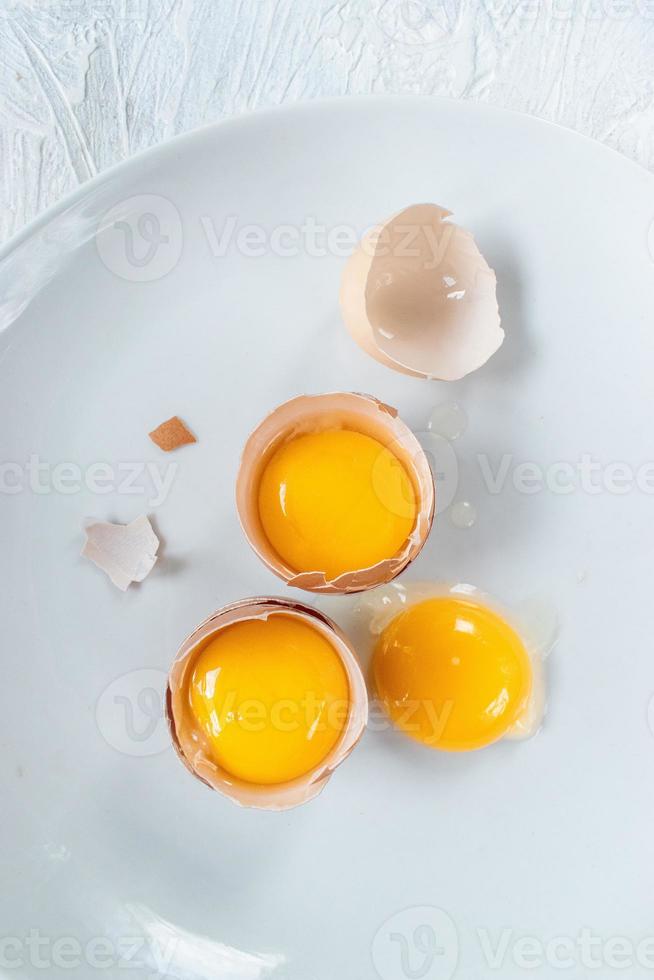 group of egg yolks in broken shells on white background flat lay photo
