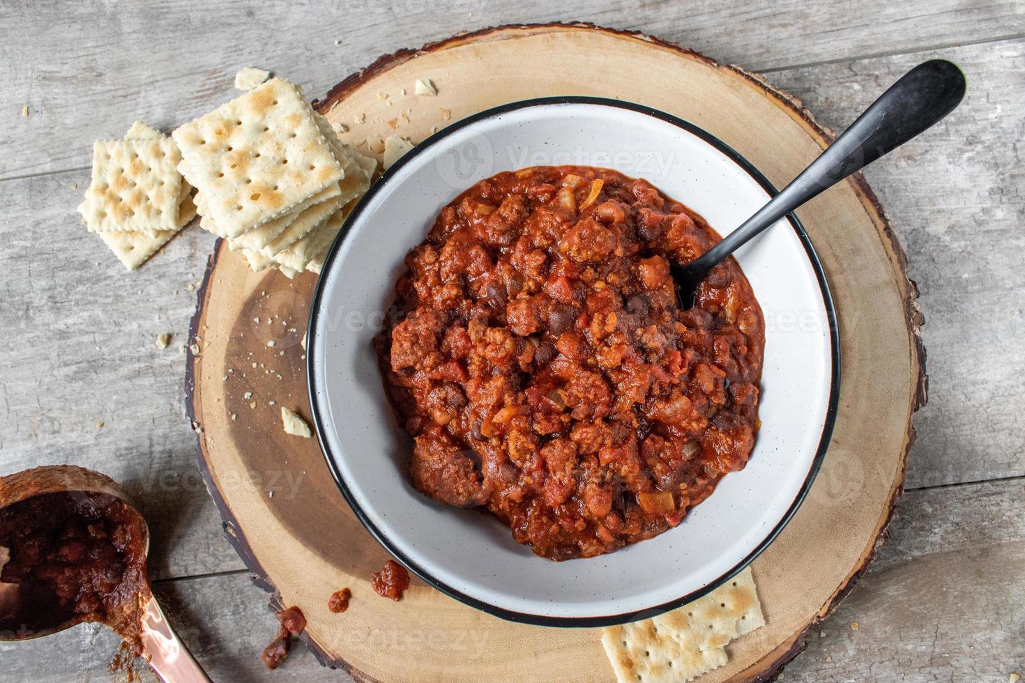 warm bowl of chili and beans with crackers in rustic setting flat lay photo