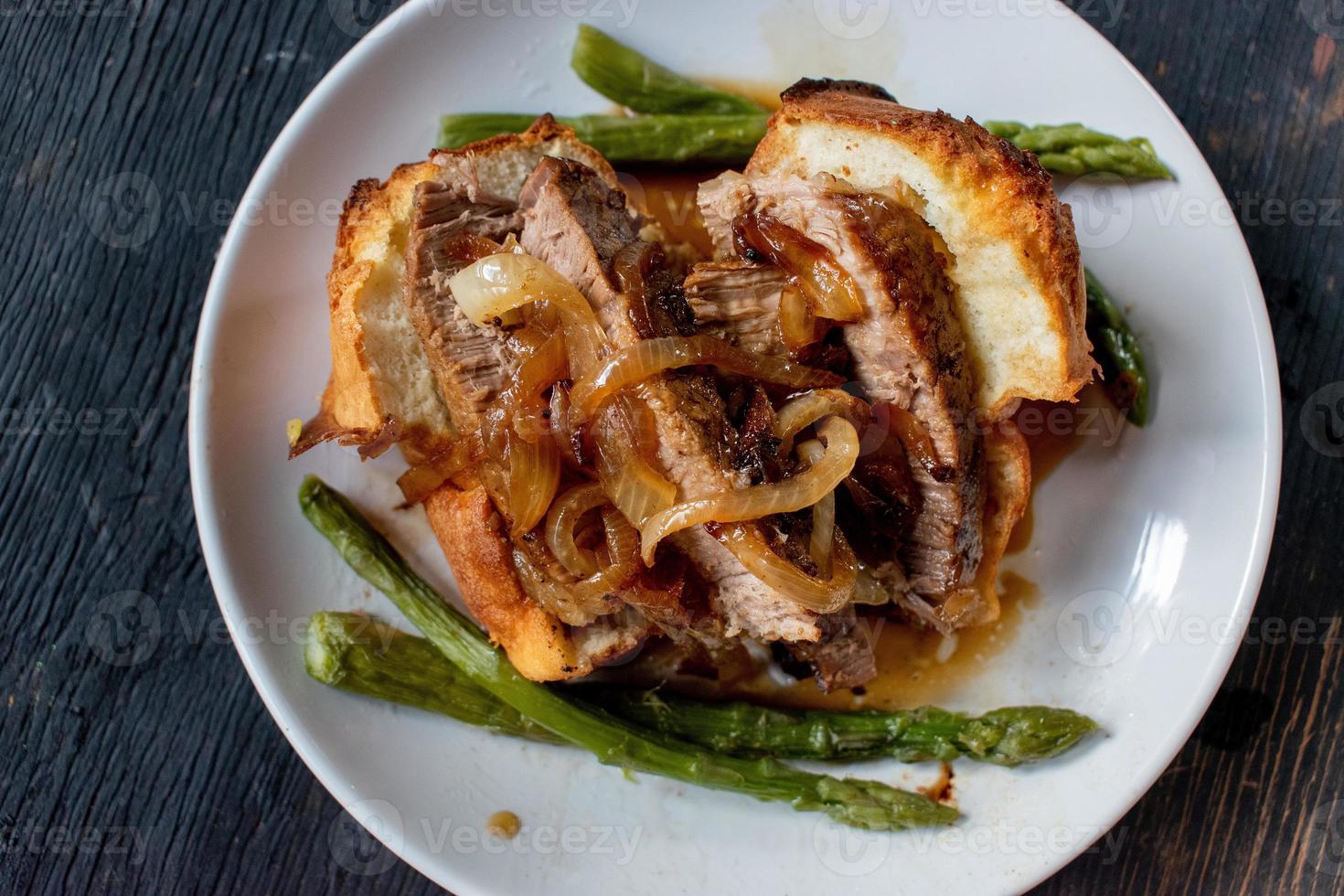 Yorkshire pudding with beef, caramelized onions, and asparagus on plate photo