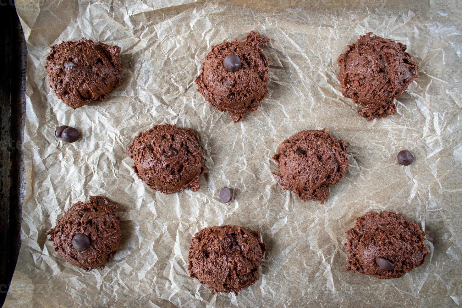 sacar la masa para galletas con trocitos de chocolate en una bandeja para hornear de papel encerado plana foto
