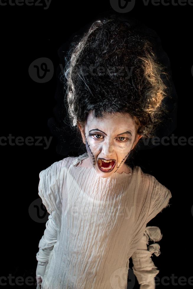 foto de estudio retrato de una joven disfrazada de halloween, cosplay de la aterradora novia de frankenstein posan sobre un fondo negro aislado