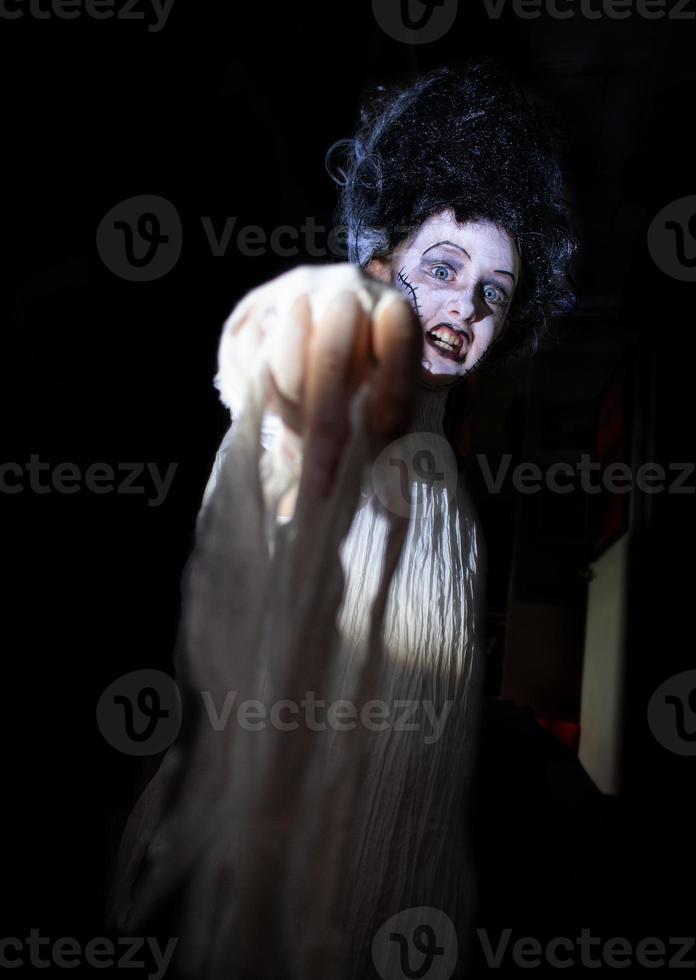 foto de estudio retrato de una joven disfrazada de halloween, cosplay de la aterradora novia de frankenstein posan sobre un fondo negro aislado