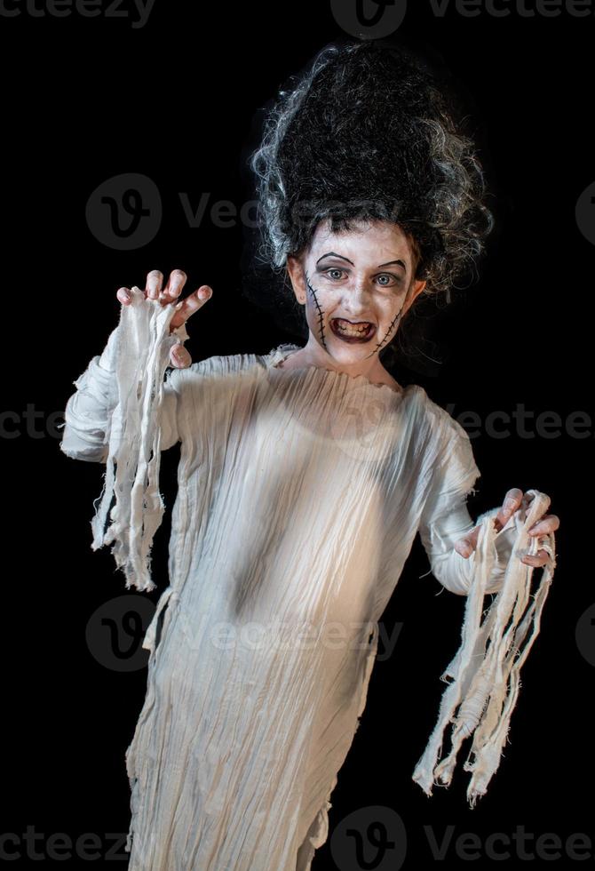 studio shot portrait of young girl in costume dressed as a Halloween, cosplay of scary bride of Frankenstein pose on isolated black background photo