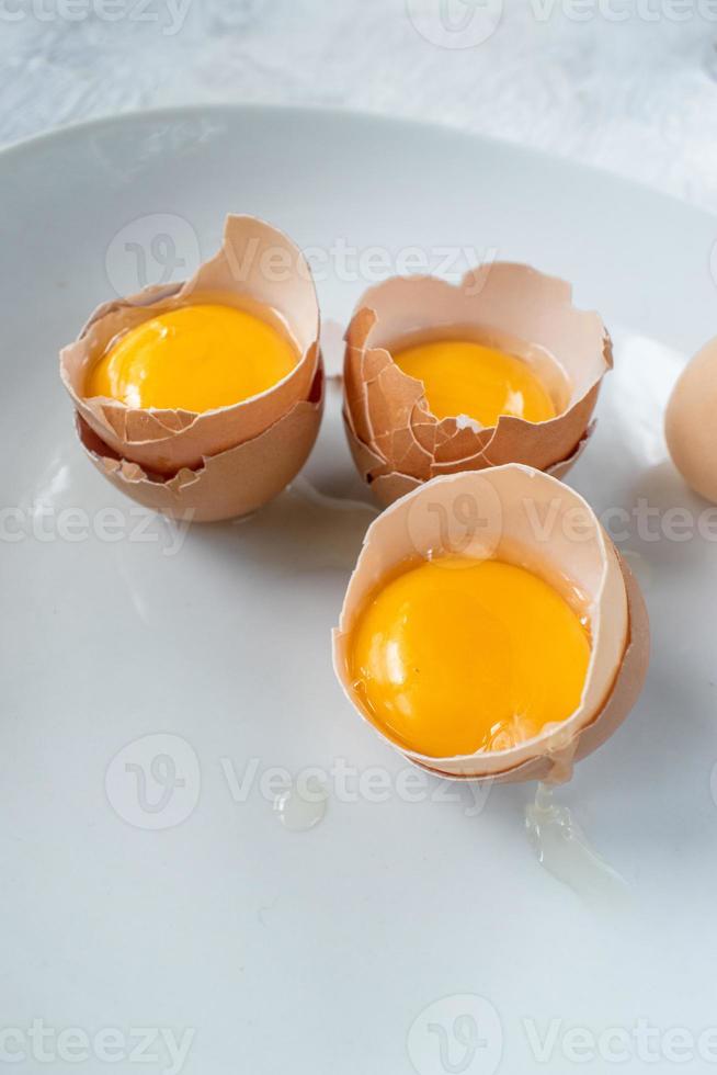 group of egg yolks in broken shells on white background photo