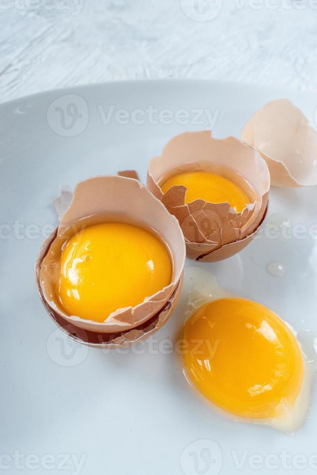 grupo de yemas de huevo en cáscaras rotas sobre fondo blanco foto