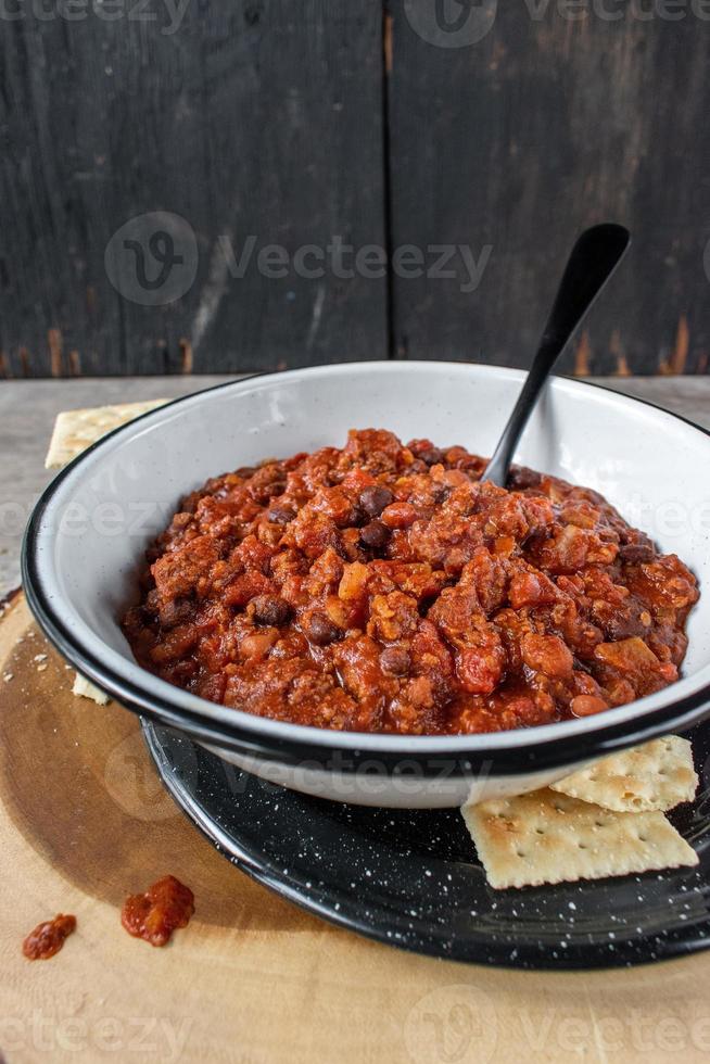 tazón tibio de chili y frijoles con galletas saladas en un entorno rústico foto