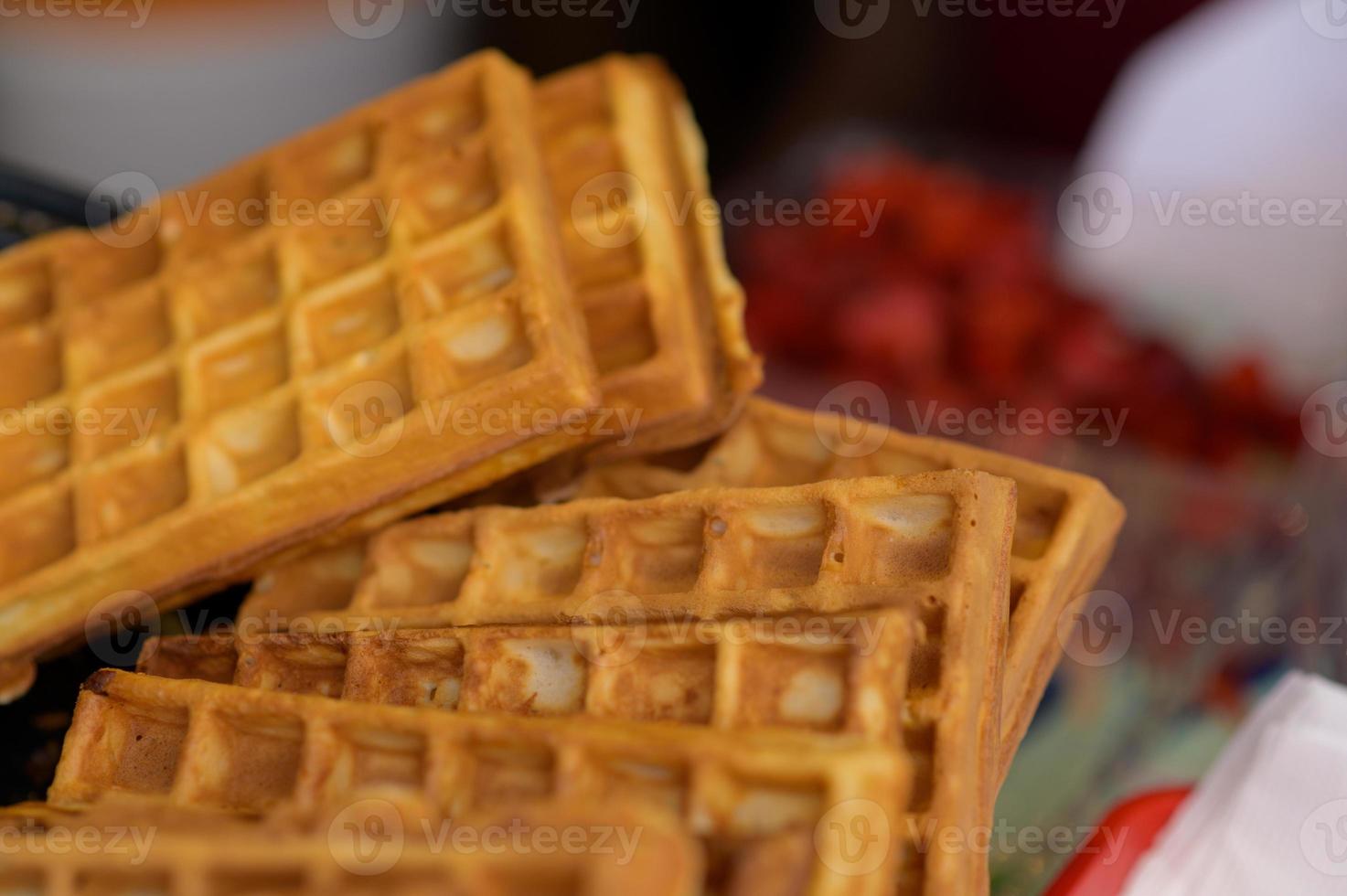 Close up of rustic traditional waffle at street food festival. Outdoor cooking service gastronomy and takeaway food concept photo