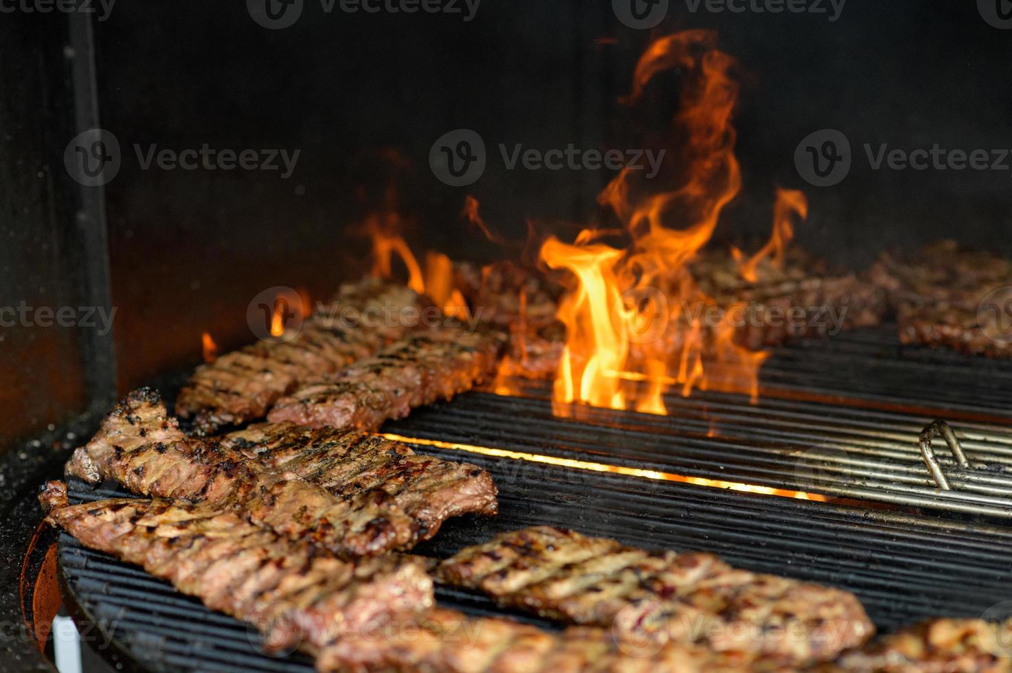 Grilled sausage with the addition of herbs and vegetables on the grill plate, outdoors. Grilling food, bbq, barbecue photo