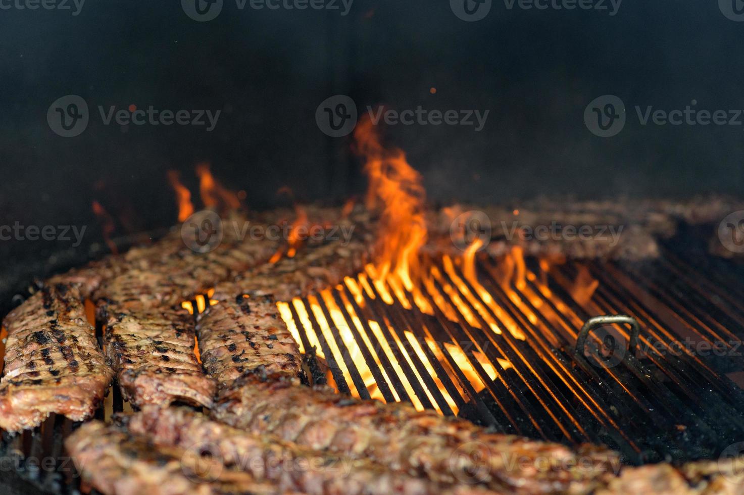 Grilled sausage with the addition of herbs and vegetables on the grill plate, outdoors. Grilling food, bbq, barbecue photo