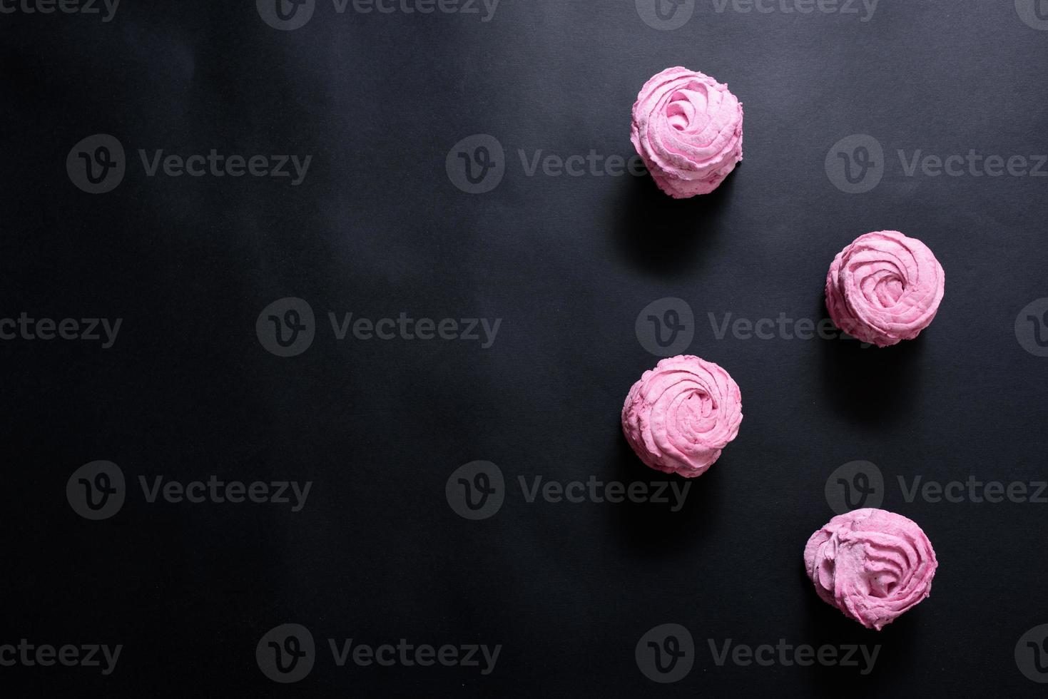 Homemade pink marshmallow on a black background. Top view photo