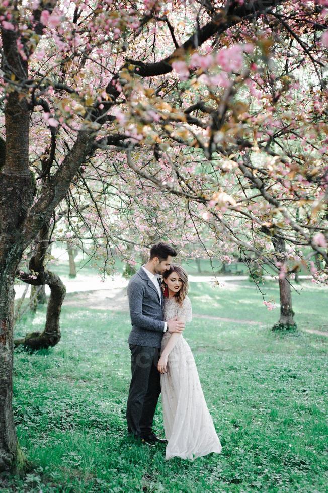 Beautiful happy bride and groom being showered with confetti from cherry blossoms photo