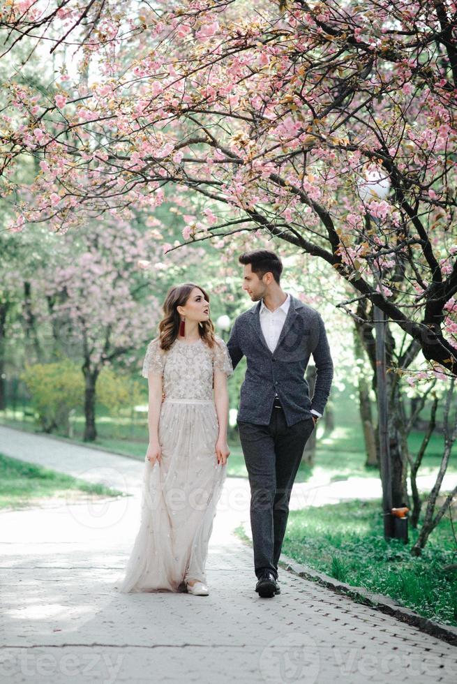 Beautiful happy bride and groom being showered with confetti from cherry blossoms photo