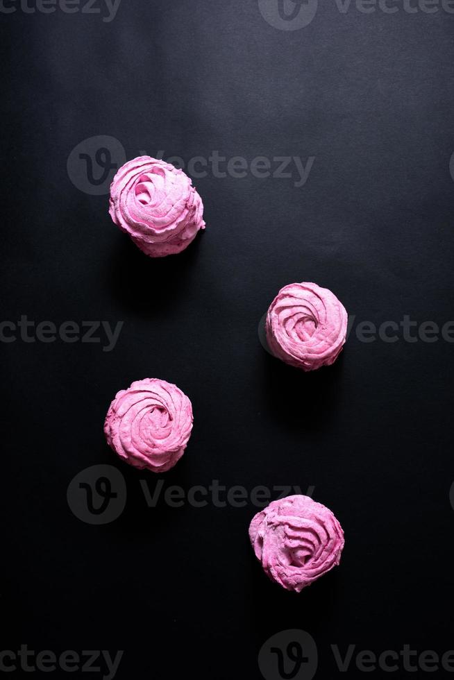 Homemade pink marshmallow on a black background. Top view photo