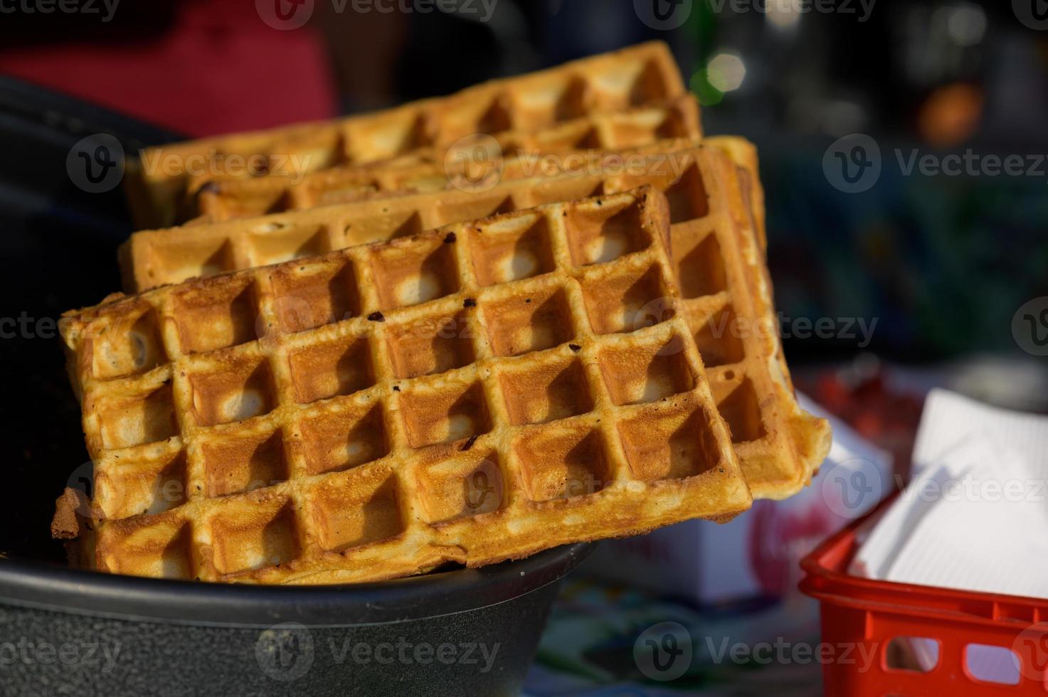 Close up of rustic traditional waffle at street food festival. Outdoor cooking service gastronomy and takeaway food concept photo