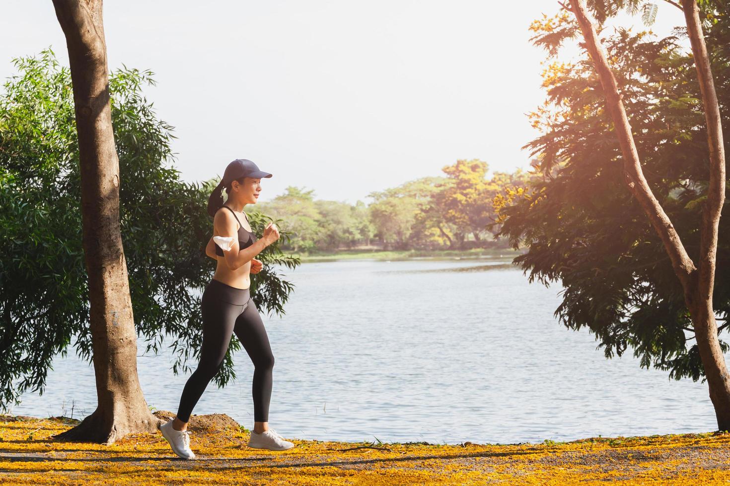 vista lateral del ejercicio de la mujer corriendo en el parque cerca del lago por la mañana. foto