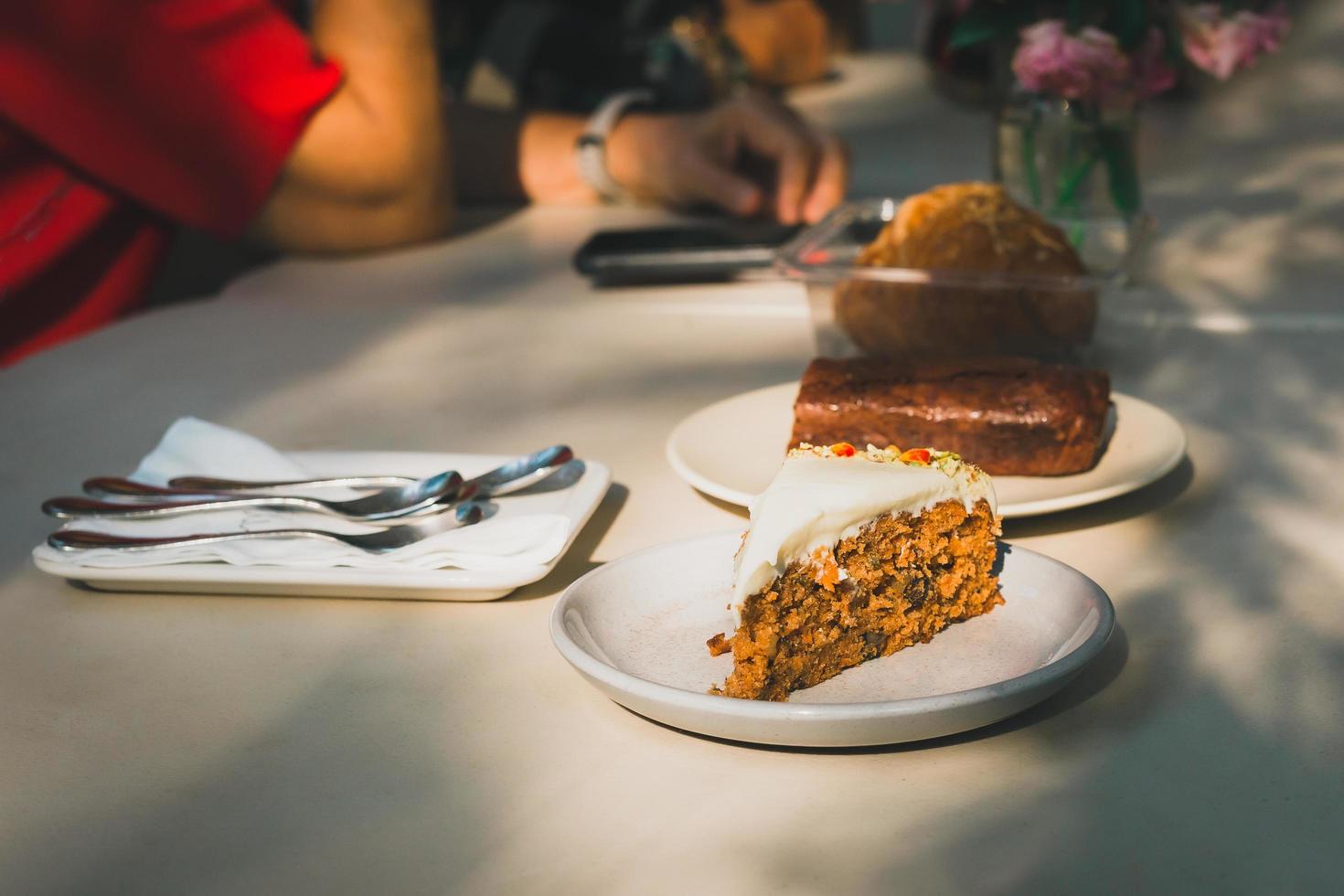 Slice of carrot cake on table with woman in background in a cafe. photo