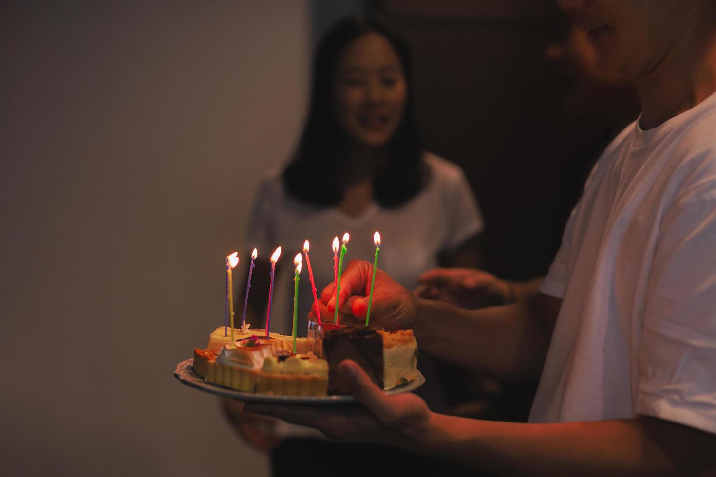 hombre sosteniendo pastel de cumpleaños con velas para cumpleañera en la casa. foto